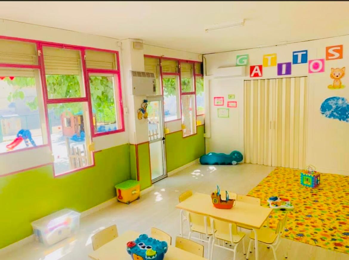 Aula Gatitos con mesas, juguetes y ventanales rojos