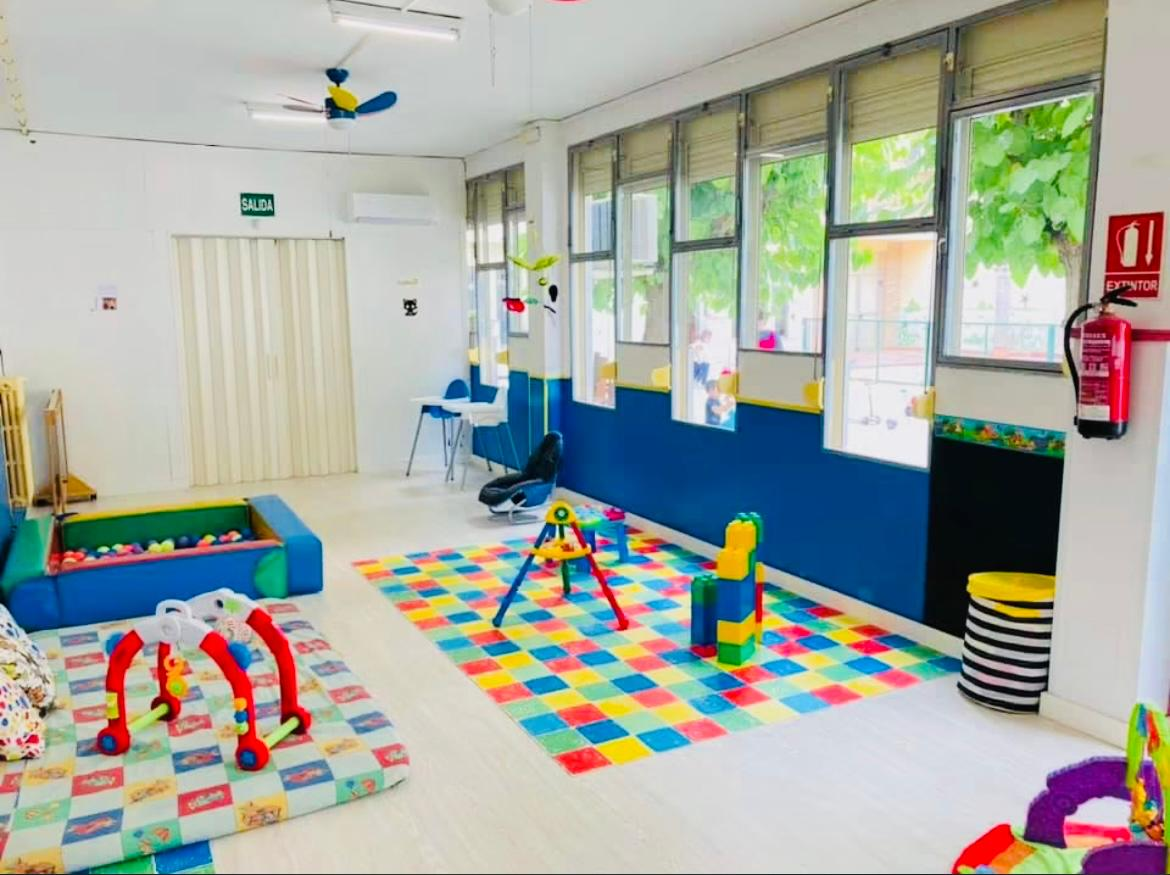 Aula de bebés con piscina de bolas, alfombra y juguetes