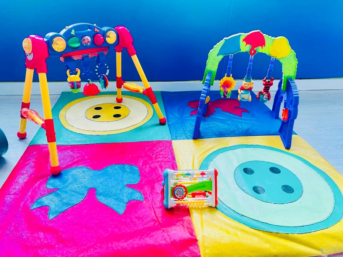 Dos gimnasios de actividades para bebés sobre alfombra de colores